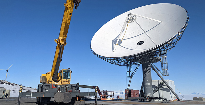 A construction crane lifts the top of the radome shelter in place